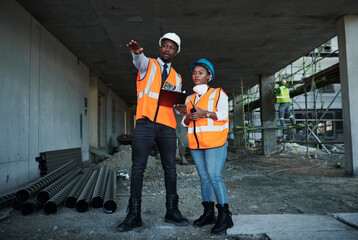 Quality is their specialty. a young man and woman having a discussion while working at a construction site.