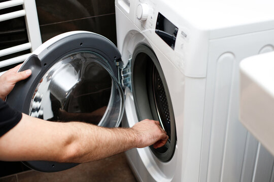 Man opens washing machine in bathroom at home