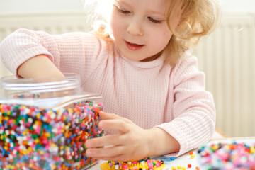 Close-up portrait of a 3-year-old girl playing Hama Beads
