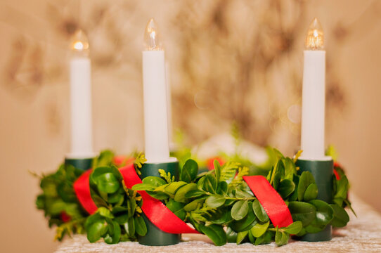 Plastic lingonberry crown with red satin ribbon and white electric lights. Saint Lucias traditional candlelight crown in closeup.