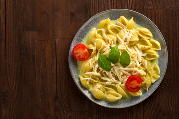 Pasta in cream sauce with cheese garnished with spinach and cherry tomatoes with a fork on a wooden table.