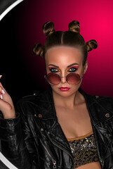 Portrait of a young sassy girl with blond hair in the studio on a pink background.