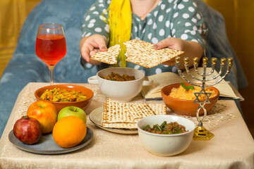 At the festive table, a Jewish woman breaks matzah.
