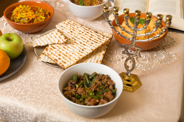 Shabbat set table with couscous, vegetables with meat, fruit, matzah and menorah.