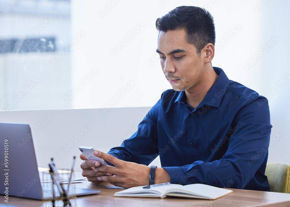 Poster a few texts just landed in his inbox. a young businessman using a cellphone in an office.