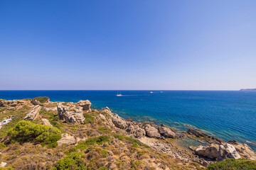 Beautiful view from mountain to blue water of Mediterranean Sea with sailing ship in distance. Rhodes Island. Greece.