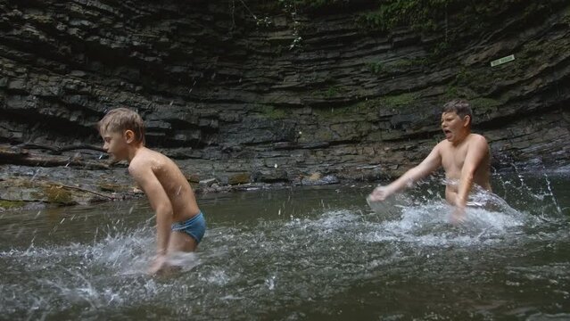 Young boys bathing in a small lake within the mountain. Creative. Little boys splashing cold water. Generative AI