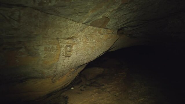 steadicam wide shot of walls and ceiling of an underground sandstone cave with exit to the light