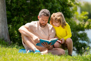 Father and son enjoy spending quality time reading books outdoors. Portrait of father and son relax...