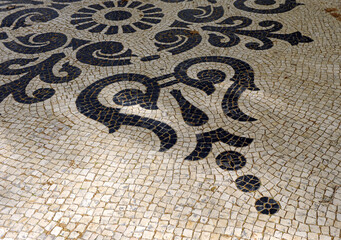 Decorative mosaic of Portuguese cobblestones (calçada portuguesa) on the sidewalks of Avenida da Liberdade in Lisbon, Portugal. Decoration of floral patterns with stones in black and white
