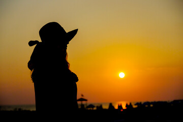 Woman in Hat Posing Against the Sunset by the Sea