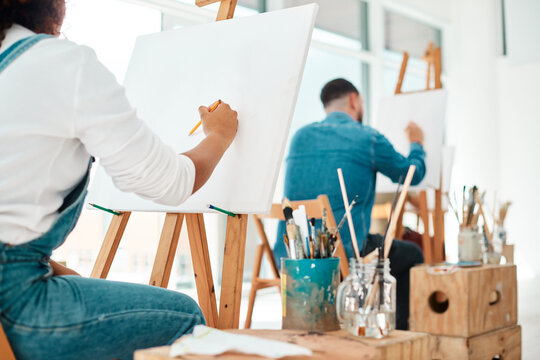 The perfect space to get creative. two unrecognizable artists sitting and sketching on a canvas during a painting session in an art studio.
