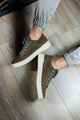 Men's summer shoes. Male legs close-up in green leather sneakers. Collection of men's leather shoes