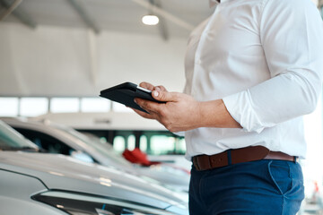browsing through a catalogue of vehicles. a car salesman using his digital tablet.