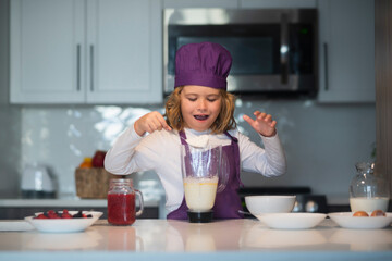 Child chef cooking meal. Chef child in apron and chef hat cooking at kitchen. Healthy food.