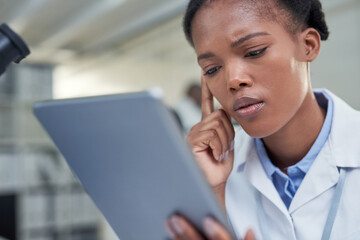 Science is all about problem solving. a young scientist using a digital tablet in a lab.