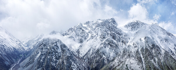 Obraz premium Aerial shot of snow covered mountain peaks shrouded in mist