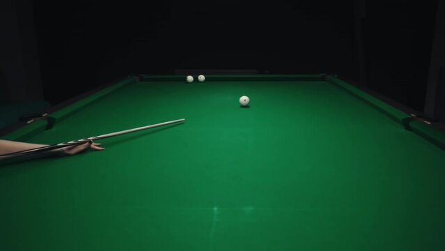 A sports game of billiards, pool or snooker on a billiard table with a green cloth.Hitting billiard balls with a cue.