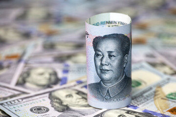Chinese yuan banknote rolled up on US dollars background. Concept of trade war between the China...