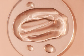 Drops and smears of cosmetics. Drops of liquid transparent gel with bubbles on a brown background.