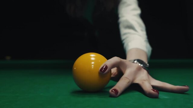 The girl puts a yellow billiard ball in the center. Woman playing snooker on green color table