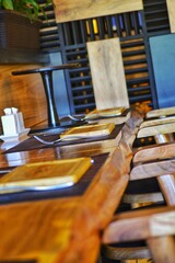 Wooden bar counter from a vertical saw cut of a tree. Loft cafe with warm lighting and brick wall. Serving with wooden utensils.
