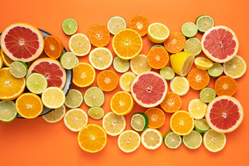 Fresh sliced and halved citrus fruits almost completely cover an orange background.