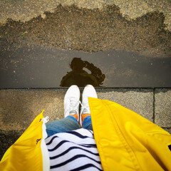 Autumn is coming - reflection of a woman with a yellow raincoat in a puddle
