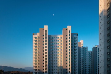 Fototapeta na wymiar View of an apartment tower in front of a blue sky with half moon on the sky in South Korea