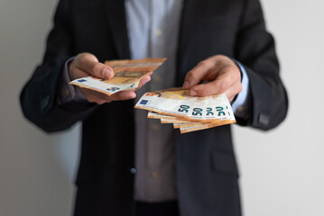 View of a man, business man dressed with a suit and shirt holding and counting fifty euros note