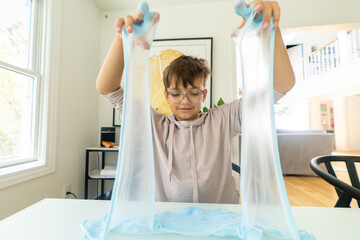 Young girl stretching blue slime with her hands

