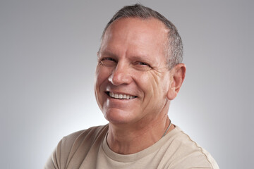Obraz premium Nothing can steal my smile. a handsome mature man standing alone against a grey background in the studio during the day.