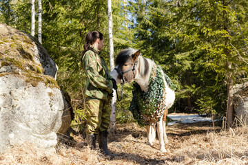 Camouflaged icelandic horse and woman in Finnish spring enviroment