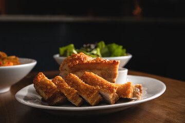 roasted pork belly with crispy skin cut in small pieces served with a fresh salad.