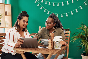 Smart tech supports that social butterfly life. two young women using a digital tablet together at a cafe.