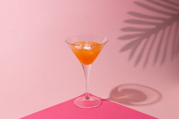 Martini cocktail with a lot of ice on a pink background, with a shadow of palm leaves, minimalist, summer concept