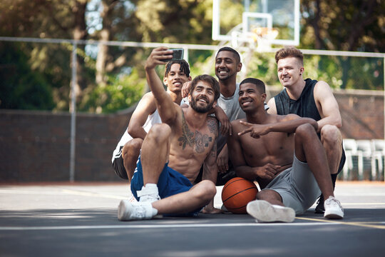 Just a bunch of basketball lovers. a group of sporty young people taking selfies together on a sports court.
