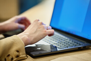 Female hands typing on laptop keyboard, close up. Woman using laptop in office. Online work