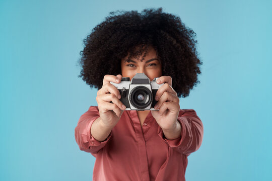 Youre cute, can I take your picture. Studio shot of a young woman using a camera against a blue background.