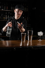 Bartender prepares classical Clover club alcoholic cocktail at the bar. Bartender mixes egg white, lemon, dry vermouth and gin to prepare the Clover club cocktail.