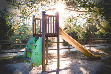 Zona de juegos infantiles en el parque. Zona de juegos entre los árboles del bosque, con la luz del atardecer y los rayos de sol entre las ramas.