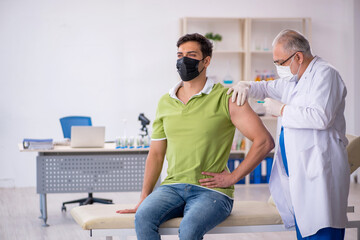 Fototapeta premium Young male patient visiting old male doctor in vaccination conce