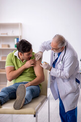 Obraz premium Young male patient visiting old male doctor in vaccination conce