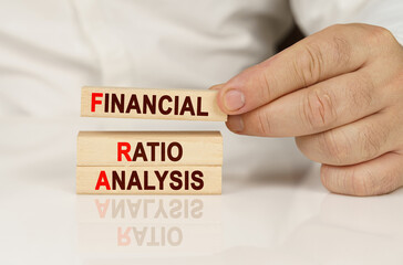 In the hands of a person and on a reflective surface are wooden blocks with the inscription - Financial Ratio Analysis