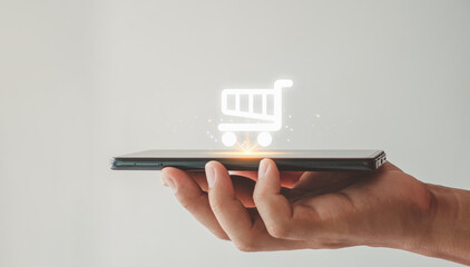 Online shopping icon on smart phone for global concept. The person's hand is holding a smartphone with a shopping cart icon. e-commerce. - obrazy, fototapety, plakaty