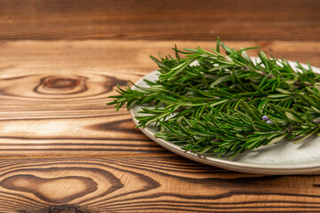 Dried rosemary in a bowl and branches of fresh rosemary on a vintage brown wooden background. Spicy spices for cooking meat and fish. Recipe. Fresh rosemary herb. Place for text, space for copy.