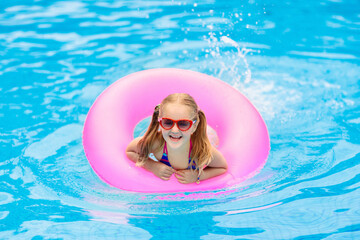 Child in swimming pool on toy ring. Kids swim.