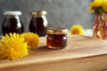 A jar of dandelion syrup with yellow dandelion flowers