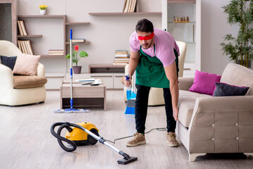 Young blinfolded male contractor cleaning the house