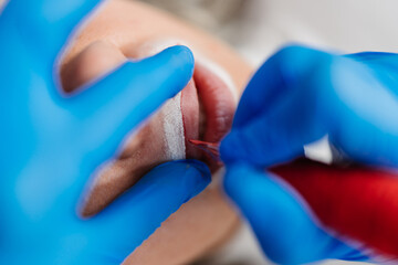 Professional permanent make up procedure. Tattoo lips makeup treatment in modern beauty salon.